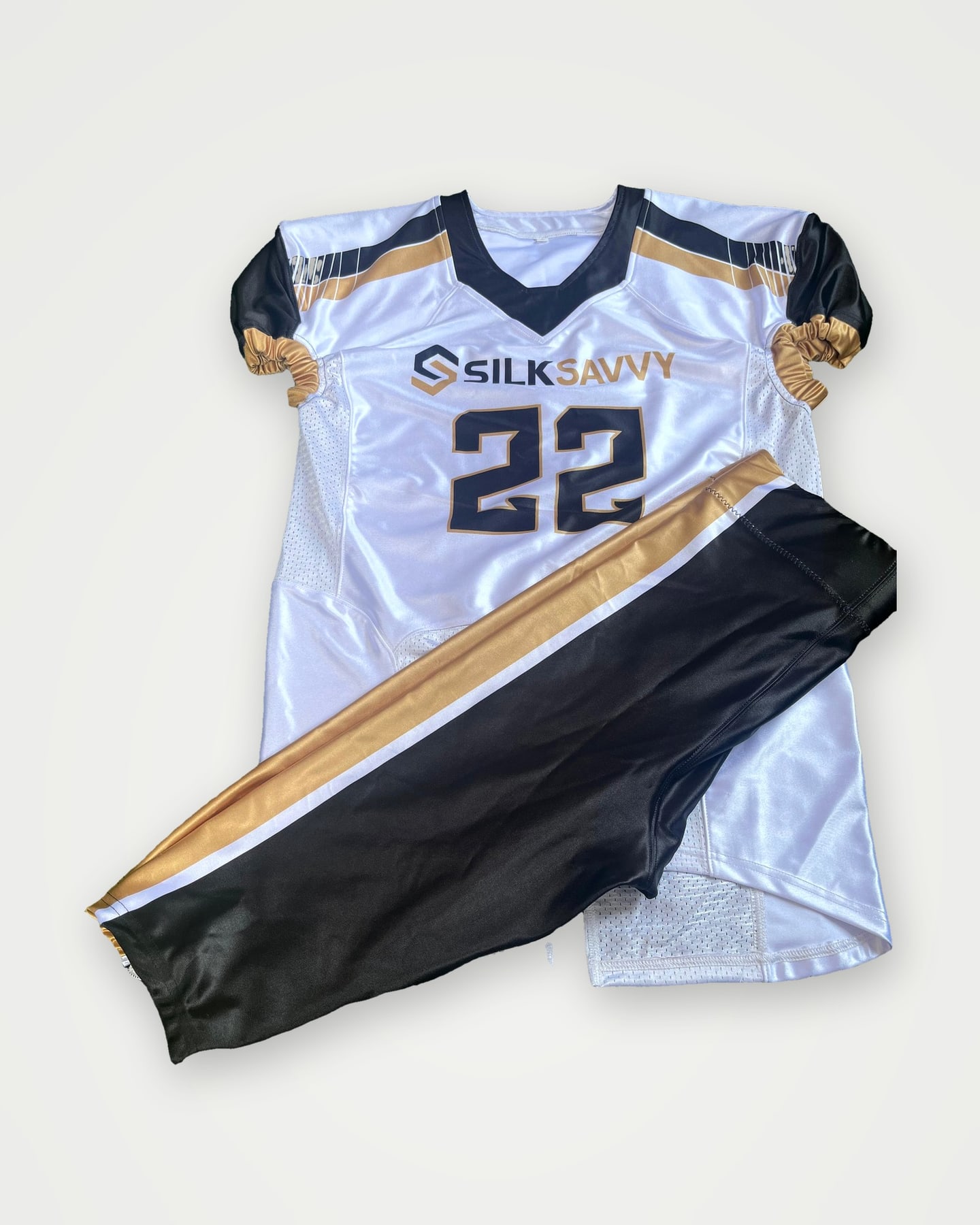 White American football jersey in navy and gold with the Silksavvy logo and number 22, laid flat with matching pants