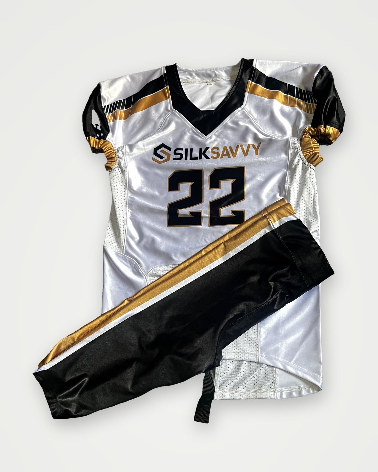 White, navy and gold American football jersey and pants set laid flat