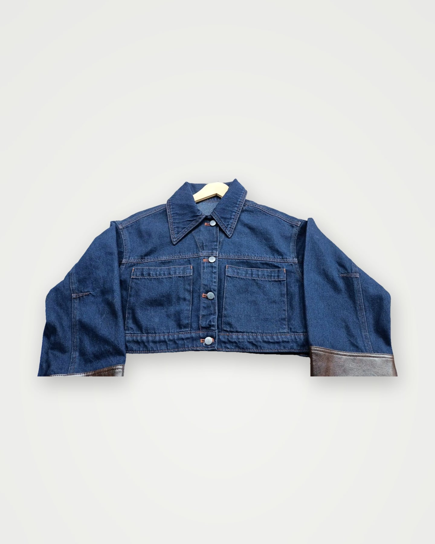 Cropped blue denim jacket on a hanger