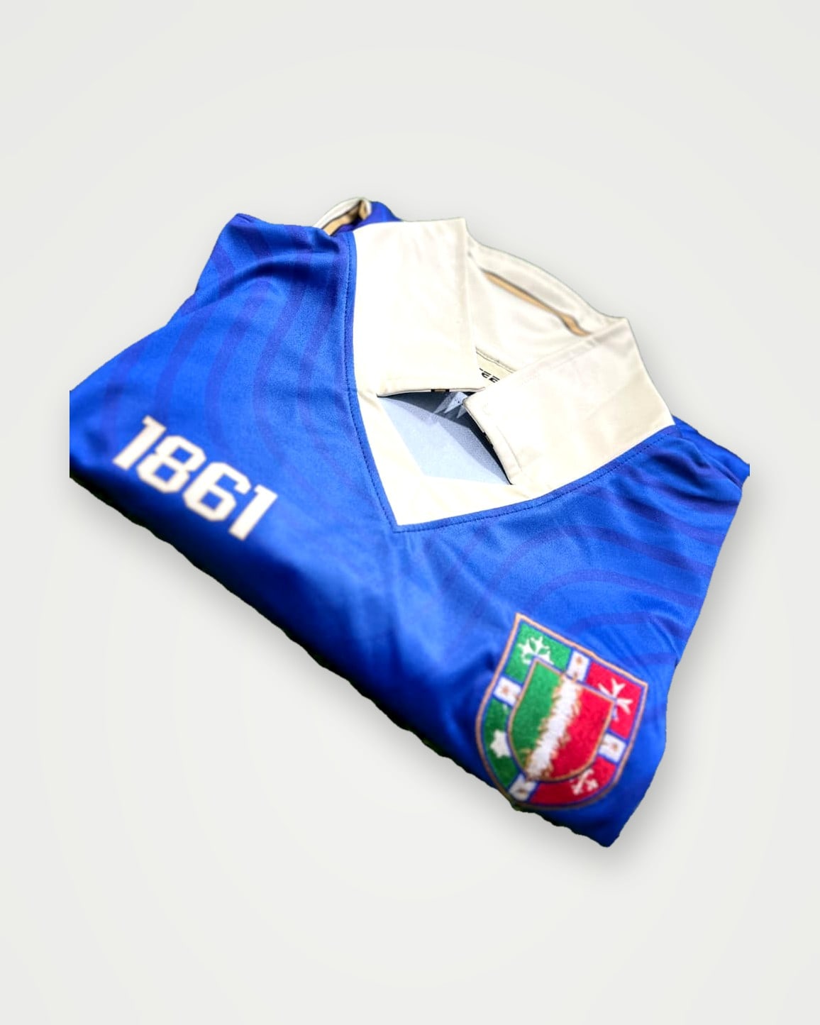 Folded blue football shirt showing the collar, crest and sleeve print