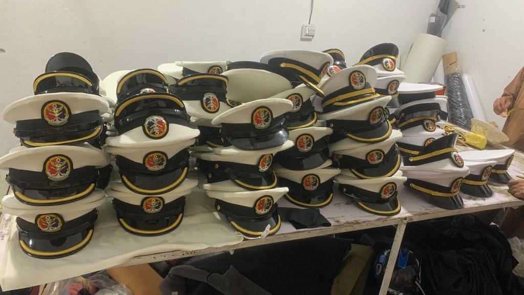 Rows of white-top peak caps with embroidered badges