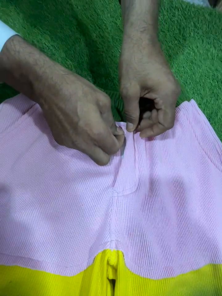 Hands checking the waistband seam of finished shorts