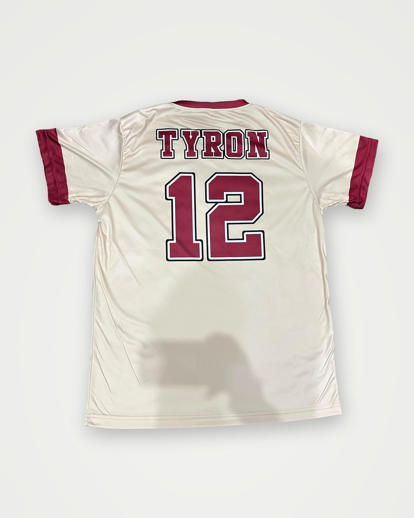 Back of a cream soccer jersey with a maroon player name and number 12