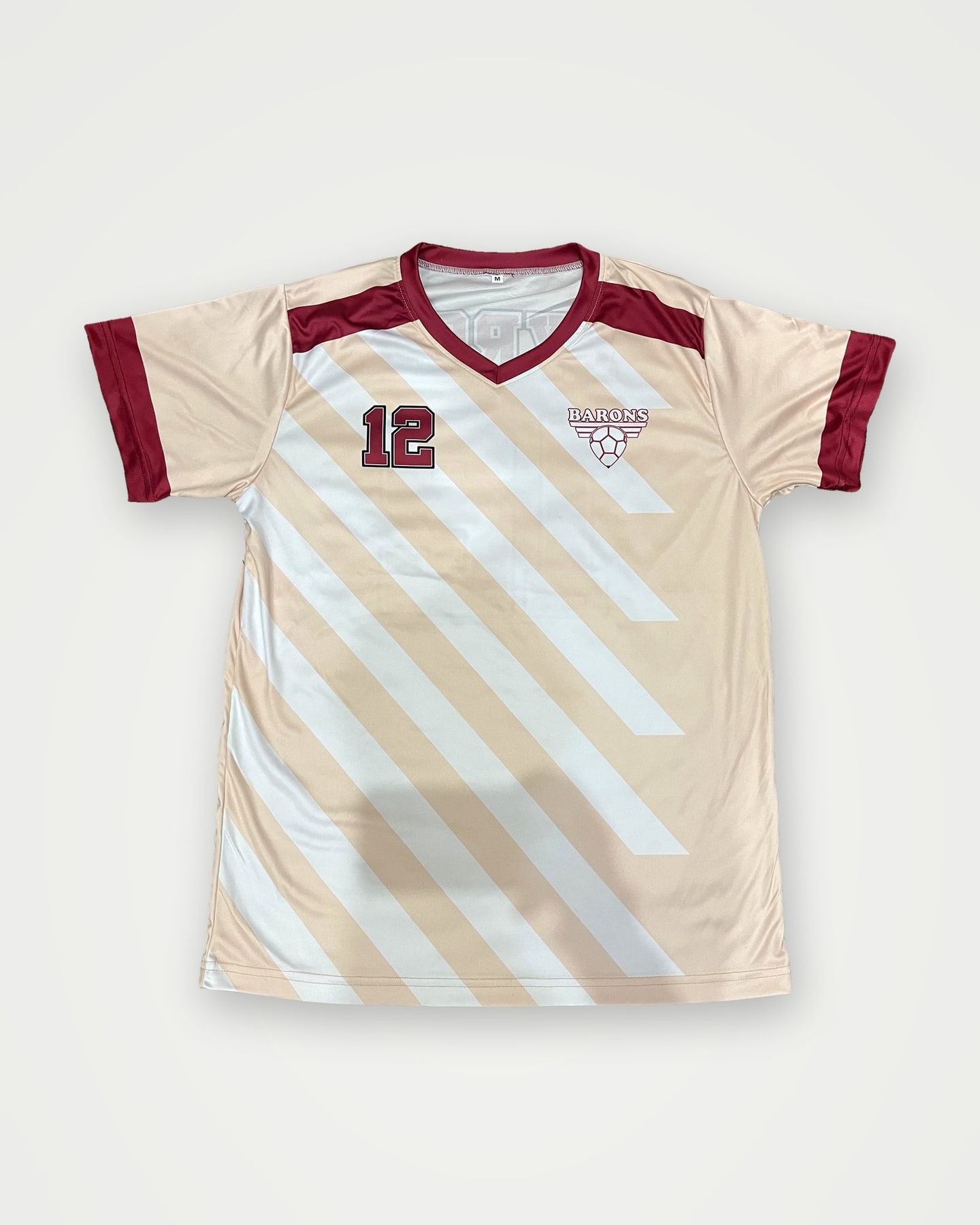Cream and maroon sublimated soccer jersey with a crest and number 12