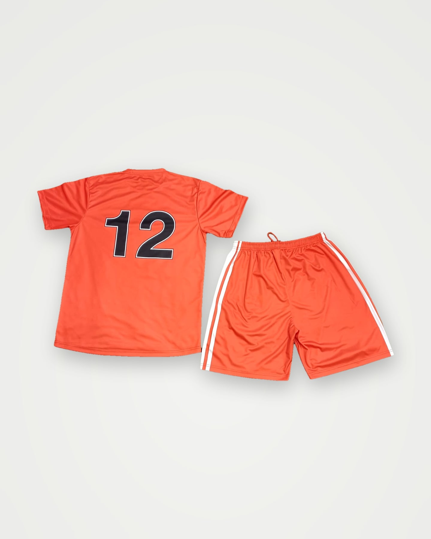 Back of an orange soccer shirt with number 12 and matching striped shorts