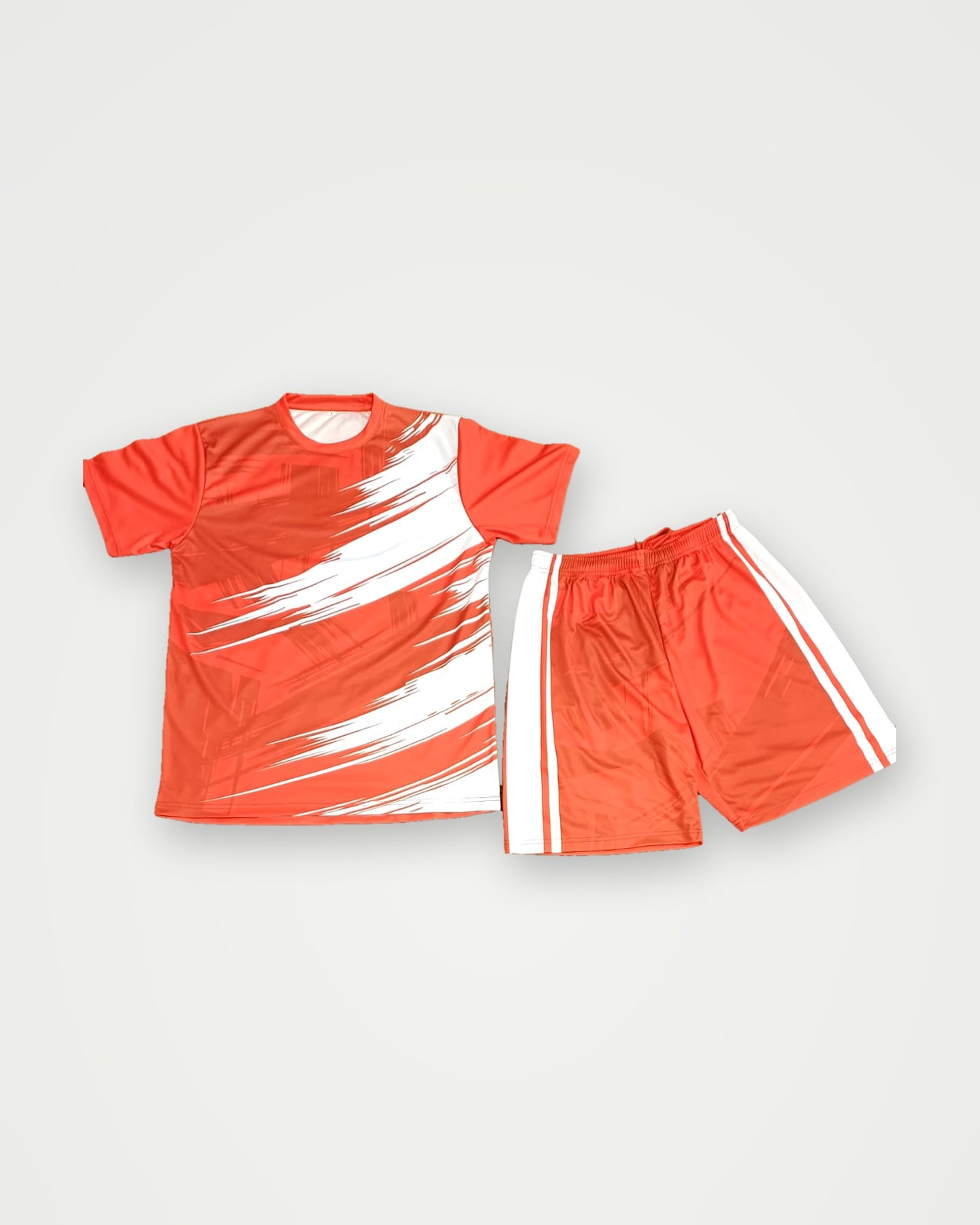 Orange sublimated soccer shirt with a white brush-stroke graphic and matching shorts